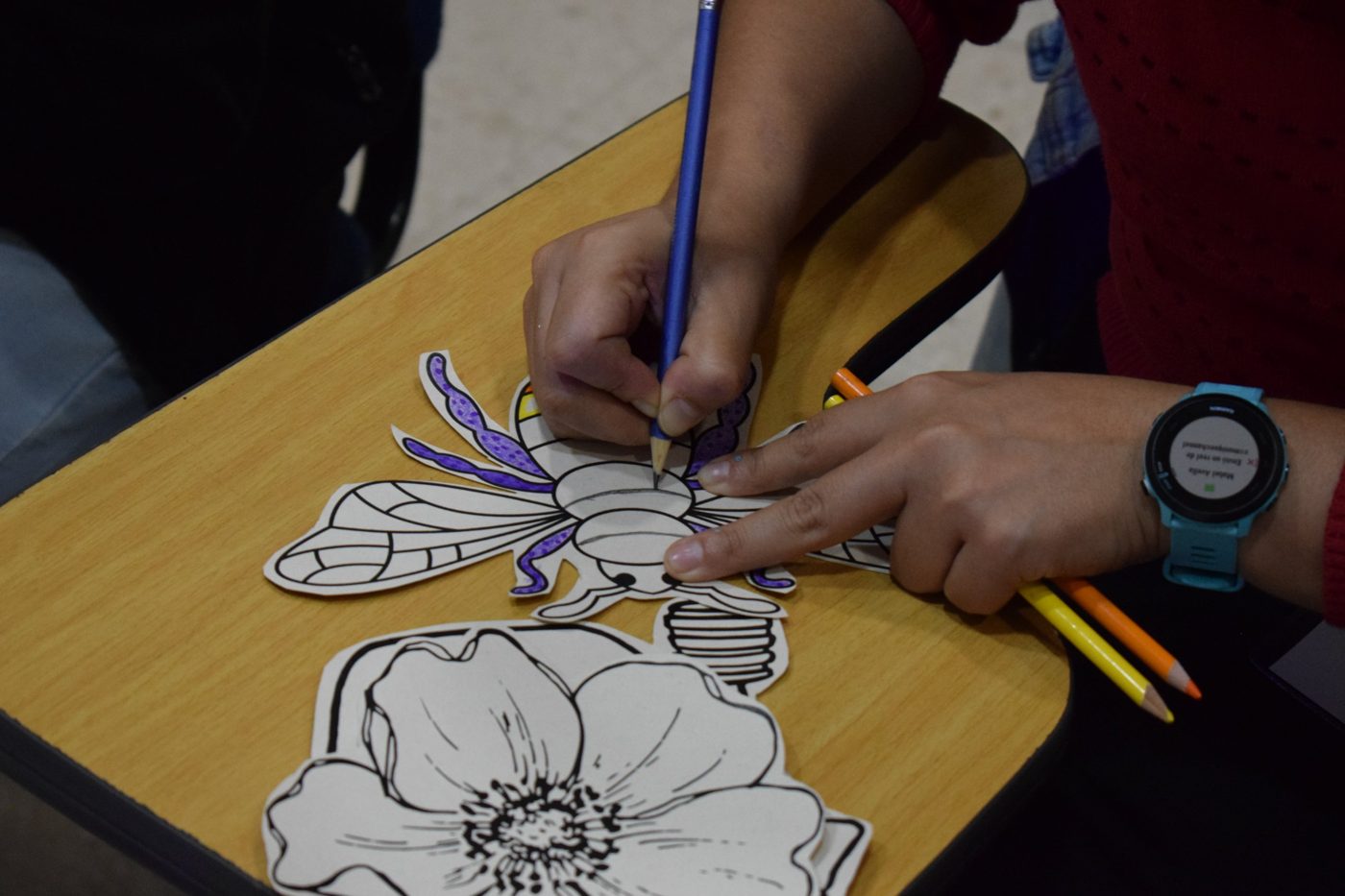 Manos que colorean una abeja de papel en un taller de bienestar laboral