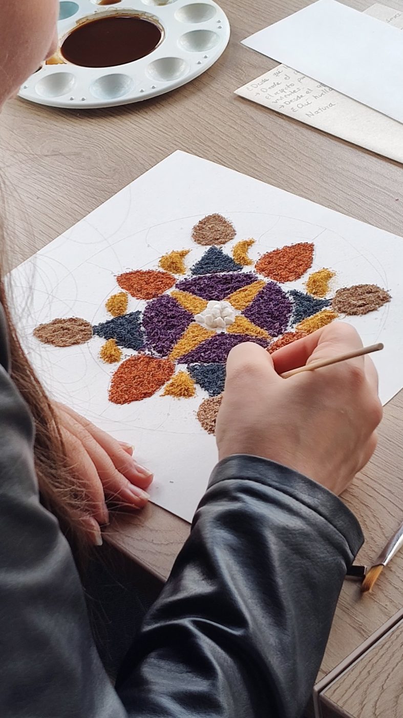 Una participante arma un mandala con arena de colores durante una sesión de gestión emocional