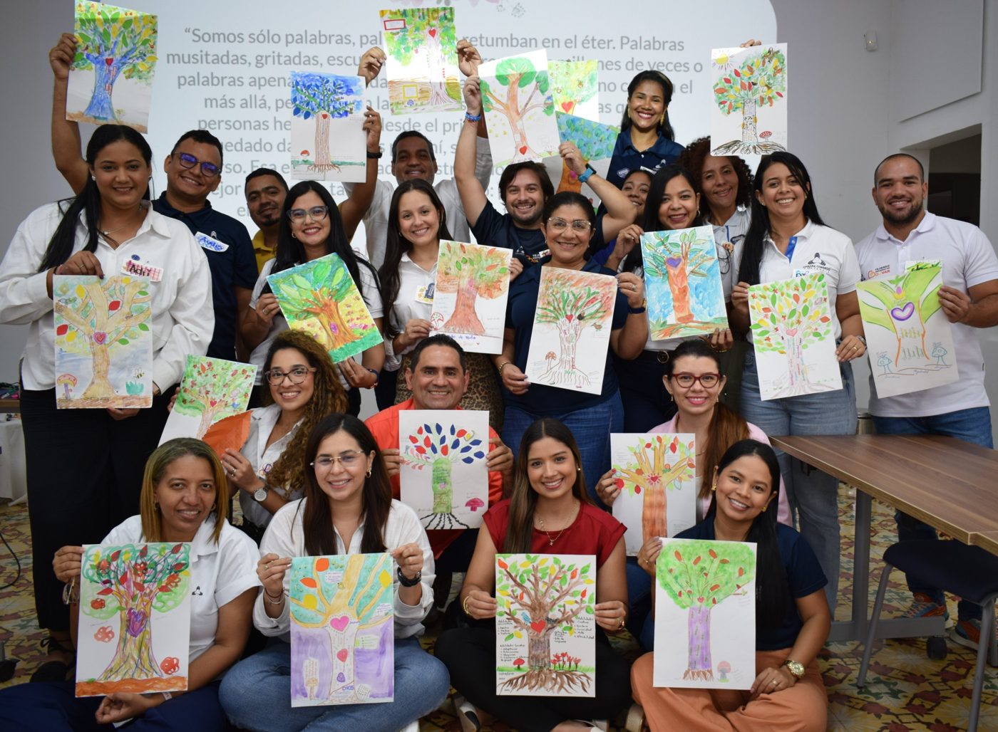 Un grupo de líderes sonríe mostrando los árboles que pintaron en acuarela durante un taller de Simoné