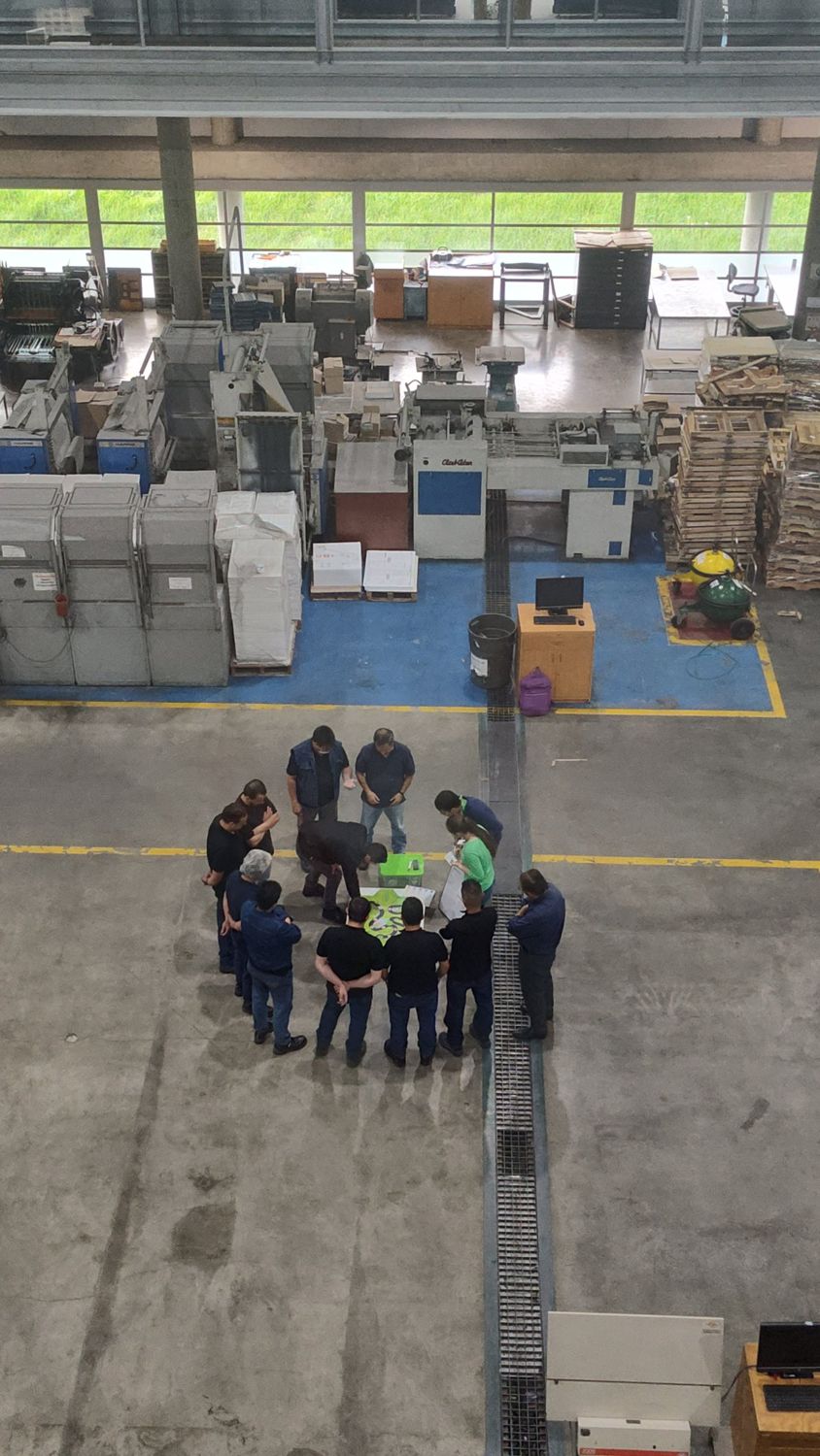 Vista desde arriba de un grupo de operarios que juega en el piso de una planta industrial